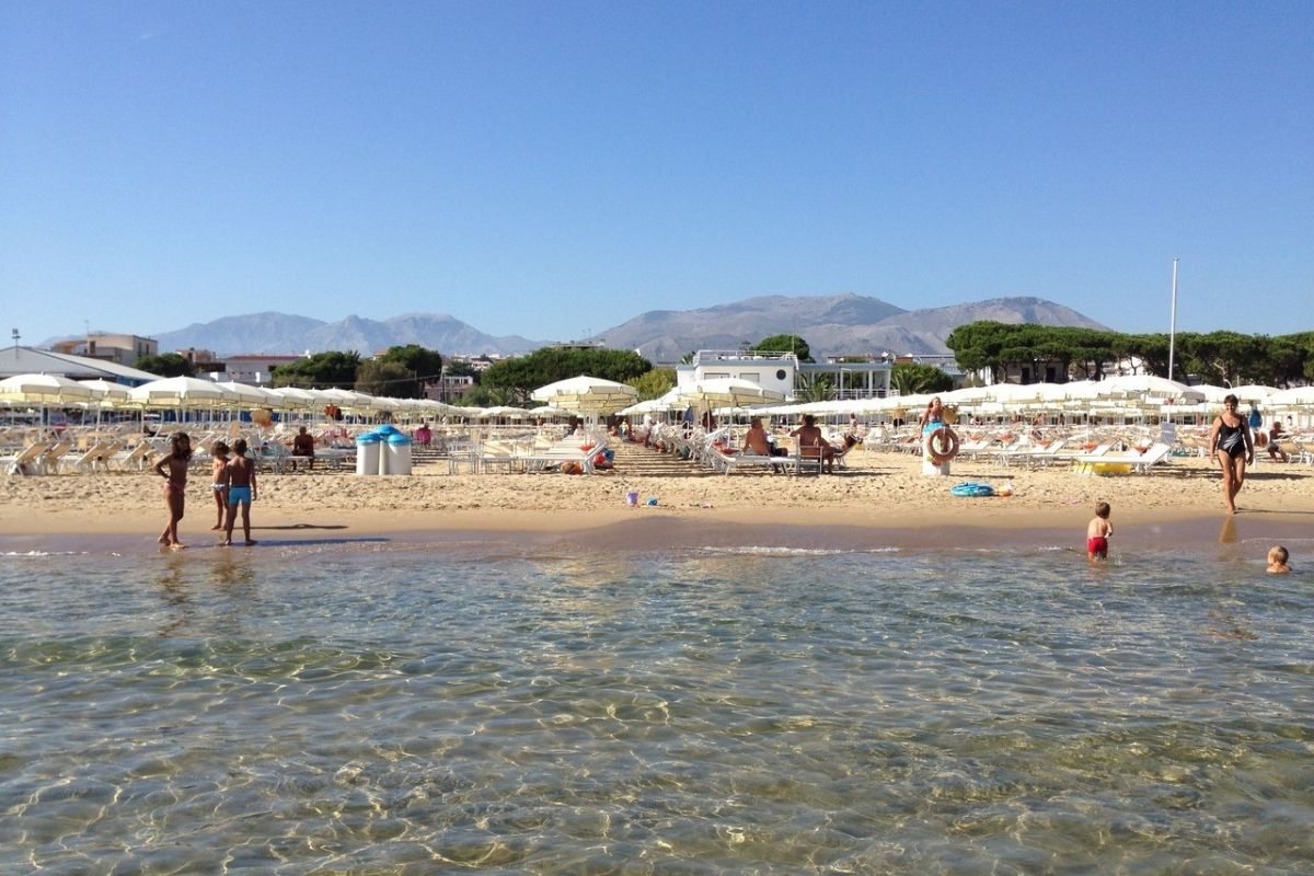 Spiaggia di Serapo con persone che si godono il sole e il mare, perfetta per rappresentare il relax estivo a Gaeta